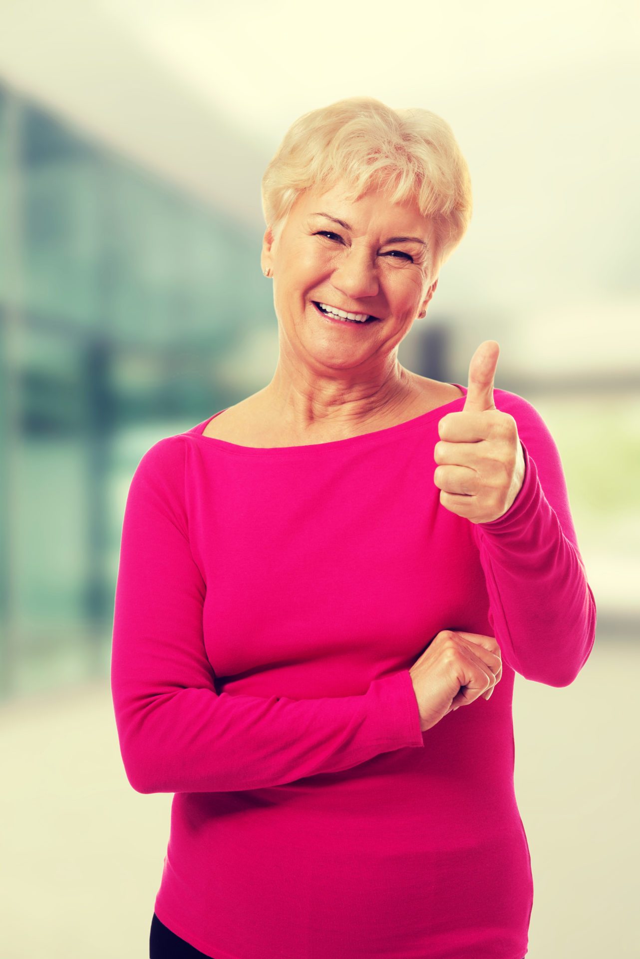 Old woman wearing pink shirt, showing OK